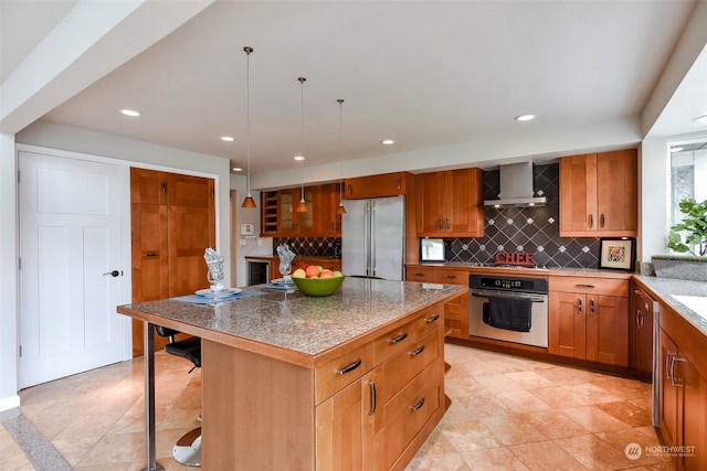 kitchen with wall chimney exhaust hood, stainless steel appliances, tasteful backsplash, a breakfast bar, and a kitchen island