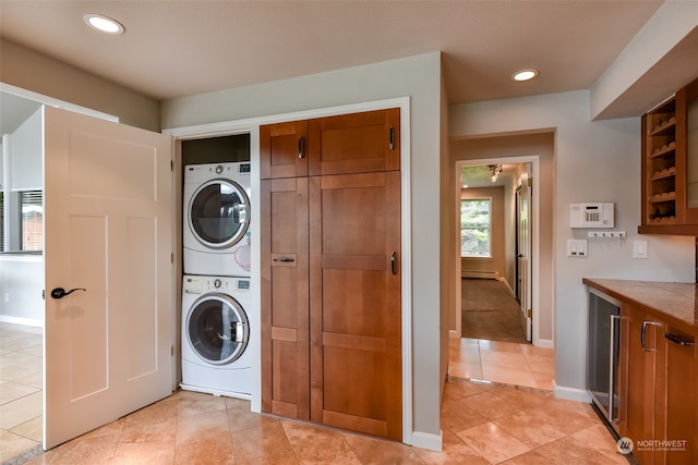 washroom featuring beverage cooler, light tile patterned floors, a baseboard radiator, and stacked washer and clothes dryer