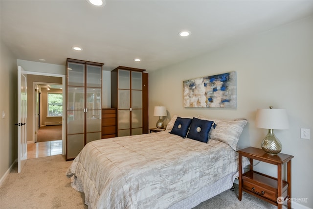 bedroom with light colored carpet and a baseboard heating unit