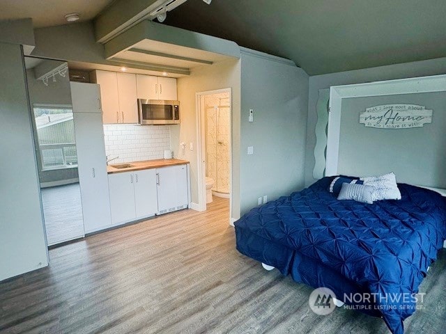 bedroom featuring beamed ceiling, sink, and light hardwood / wood-style flooring