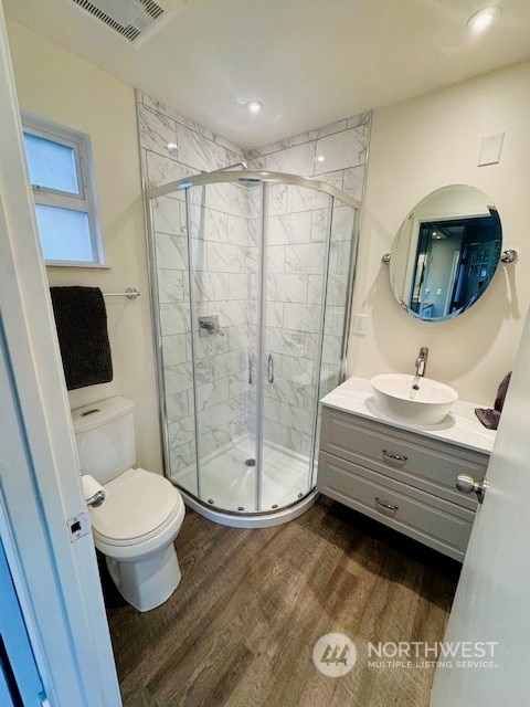 bathroom with toilet, hardwood / wood-style floors, vanity, and walk in shower