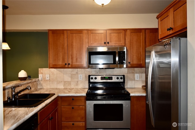 kitchen featuring pendant lighting, decorative backsplash, sink, and appliances with stainless steel finishes