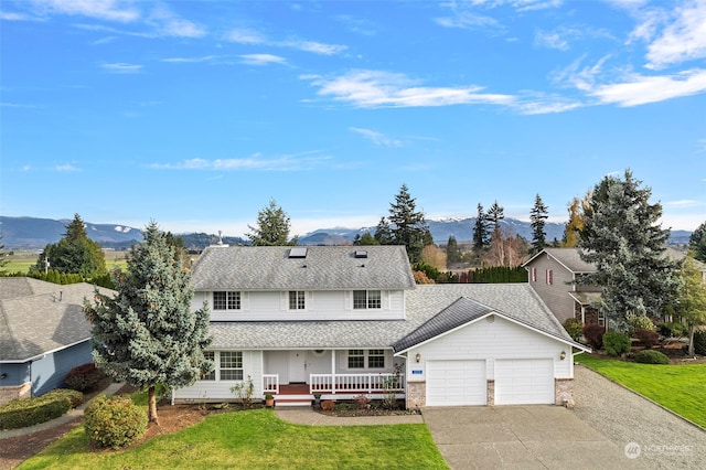 view of front of home with a mountain view, a front lawn, covered porch, and a garage