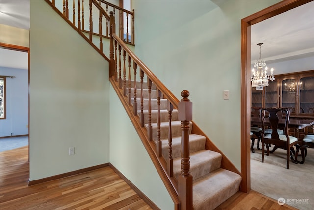 stairway with hardwood / wood-style floors and a notable chandelier