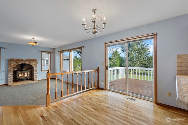 interior space with a wood stove, wood-type flooring, and an inviting chandelier