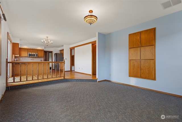 unfurnished living room featuring light carpet, an inviting chandelier, and sink