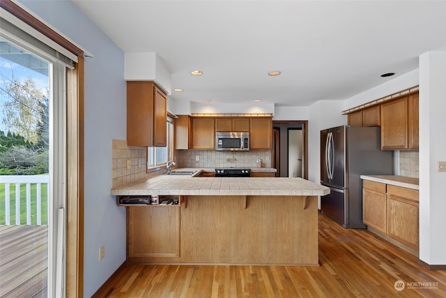 kitchen featuring kitchen peninsula, light hardwood / wood-style flooring, a healthy amount of sunlight, and appliances with stainless steel finishes