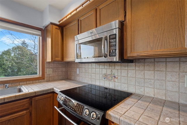 kitchen featuring tasteful backsplash, tile counters, black electric range, and sink