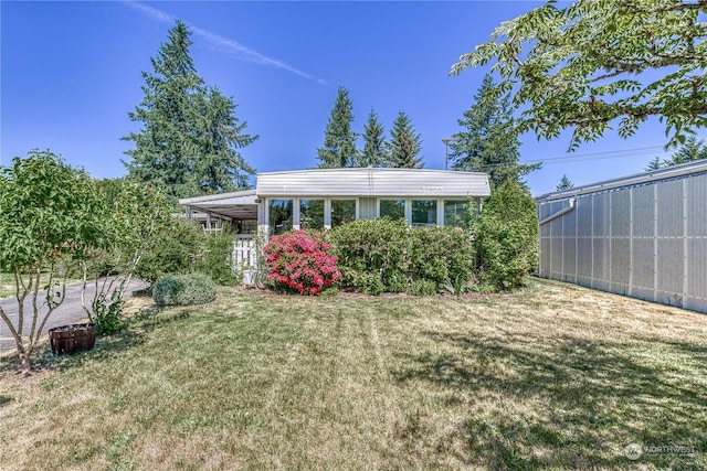 rear view of house featuring a lawn and a carport