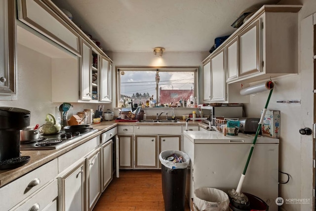 kitchen featuring sink, refrigerator, light hardwood / wood-style floors, and stainless steel gas stovetop