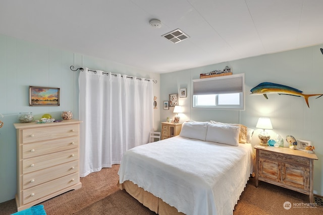 bedroom with dark carpet and wooden walls