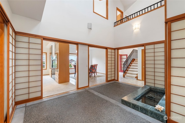 interior space with light colored carpet and a high ceiling