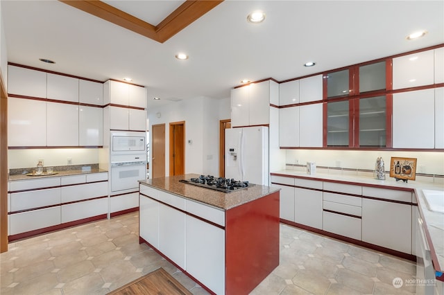 kitchen with a center island, white cabinets, and white appliances