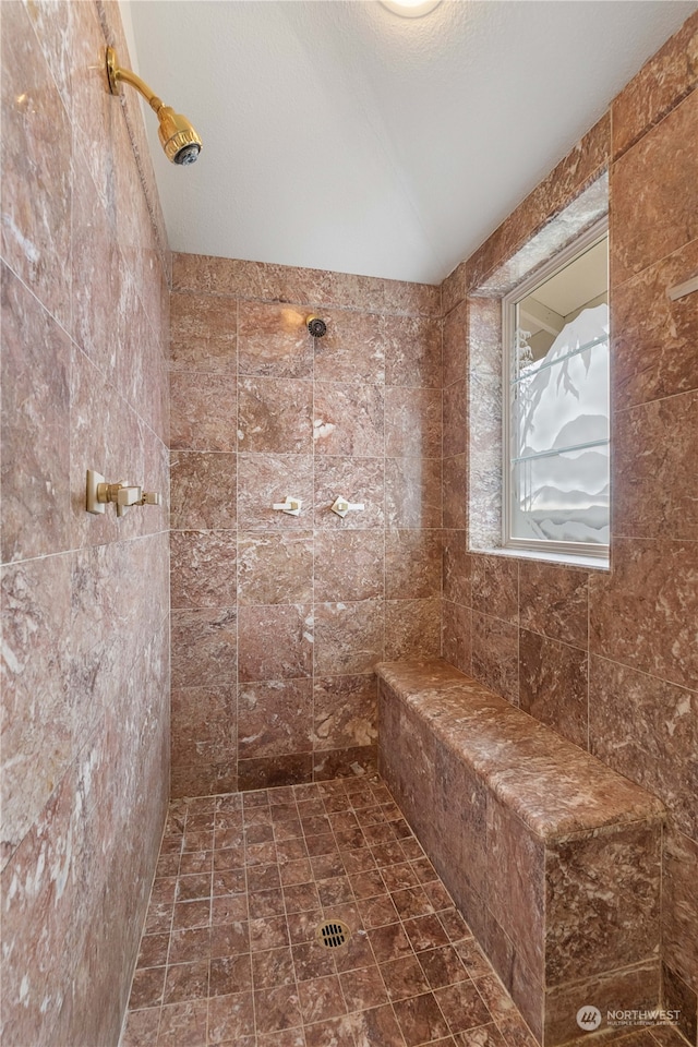 bathroom with tiled shower and a textured ceiling