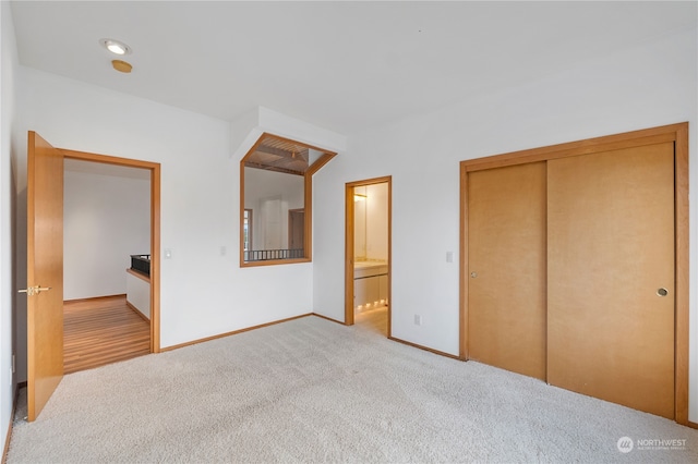 unfurnished bedroom featuring a closet, light carpet, and ensuite bath