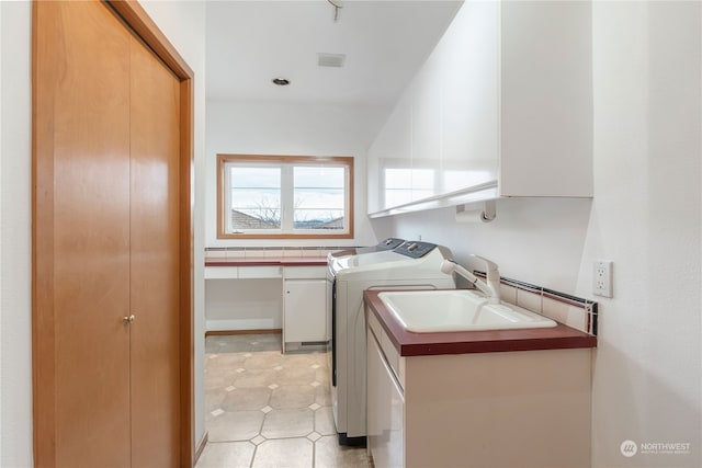 laundry room with cabinets, washing machine and dryer, and sink