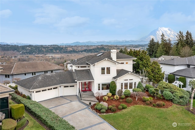 view of front property featuring a mountain view, a garage, and a front lawn