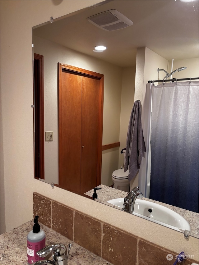 bathroom featuring sink, a shower with shower curtain, and toilet