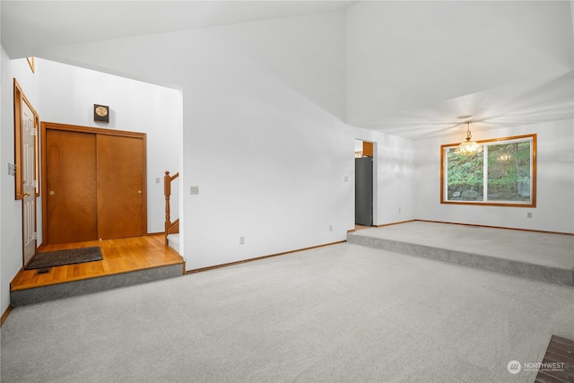 carpeted empty room featuring a notable chandelier and lofted ceiling