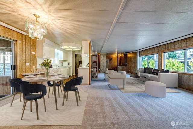 carpeted dining space with an inviting chandelier, sink, and wooden walls