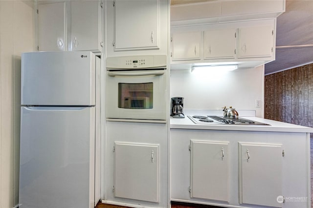 kitchen with fridge, electric cooktop, white oven, and wood walls