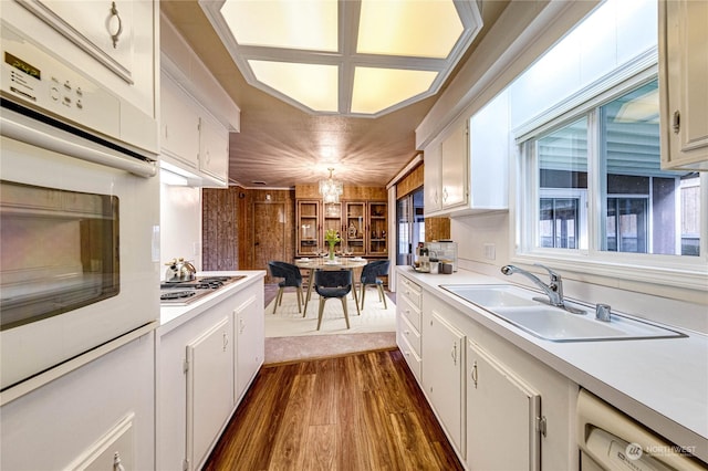 kitchen with sink, stainless steel gas cooktop, dishwashing machine, white oven, and white cabinets