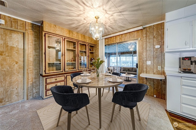 carpeted dining room with wooden walls and a notable chandelier