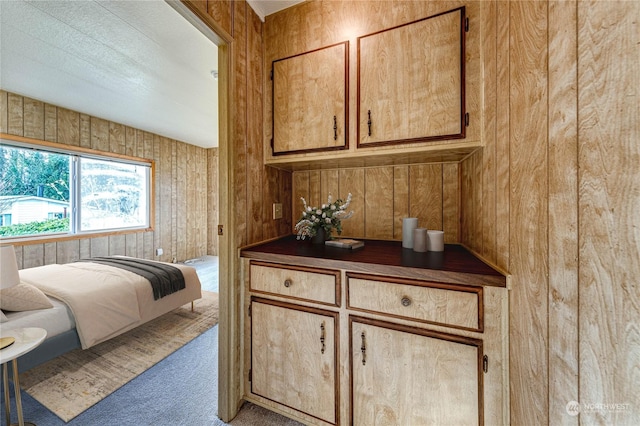 bedroom featuring light colored carpet and wood walls