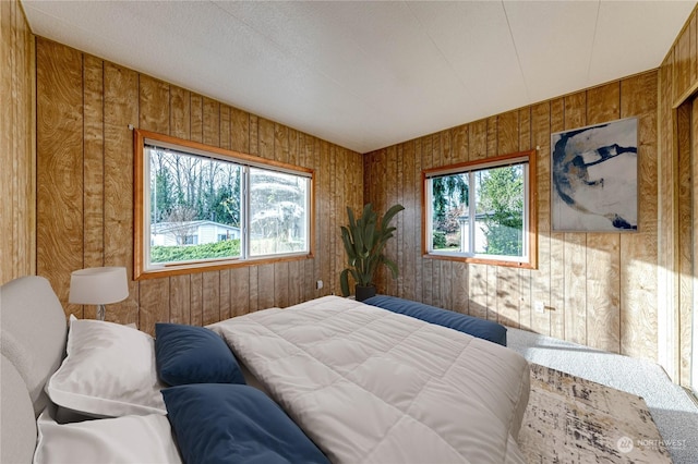 bedroom with wooden walls, carpet floors, and multiple windows