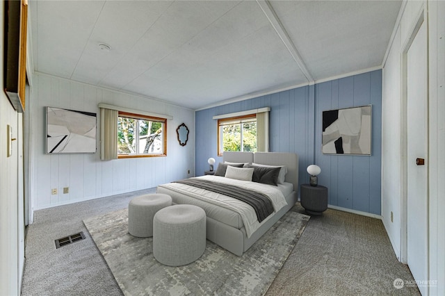 carpeted bedroom featuring multiple windows, wooden walls, and ornamental molding