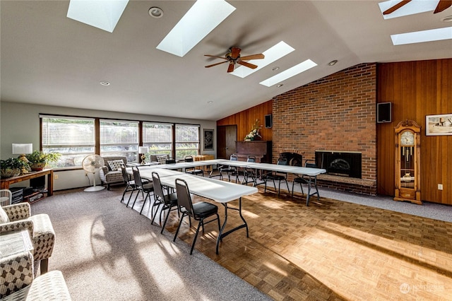 dining area with ceiling fan, wooden walls, and a brick fireplace