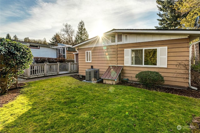 rear view of property featuring a yard and central air condition unit