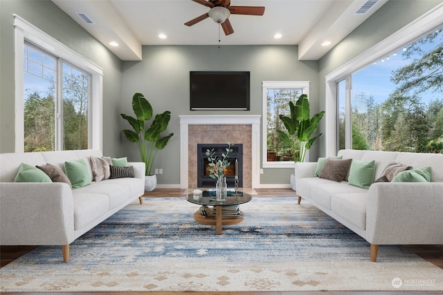 living room with hardwood / wood-style floors, ceiling fan, and a tiled fireplace