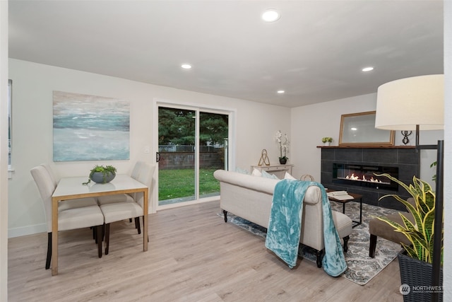 living room featuring a tile fireplace and light hardwood / wood-style floors