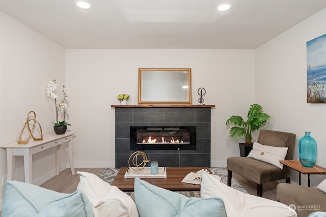 living room with wood-type flooring and a tiled fireplace