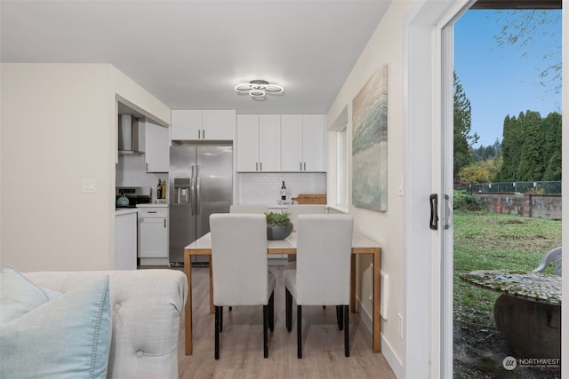 kitchen with white cabinets, wall chimney exhaust hood, stainless steel fridge with ice dispenser, and backsplash