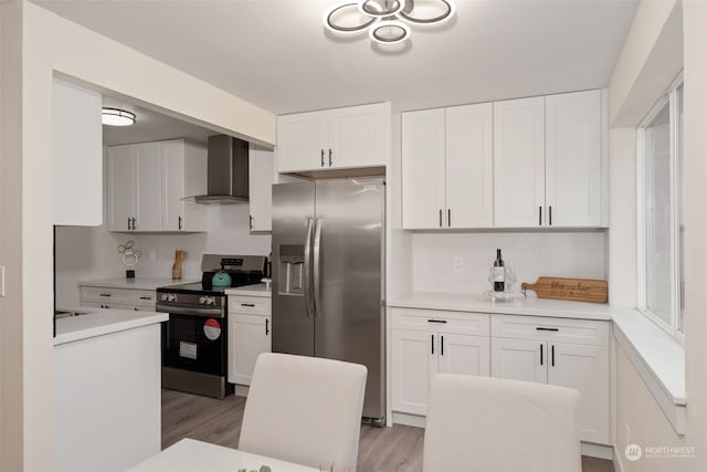 kitchen featuring white cabinets, appliances with stainless steel finishes, and wall chimney range hood