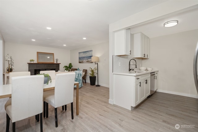 dining space with a tile fireplace, sink, and light hardwood / wood-style floors