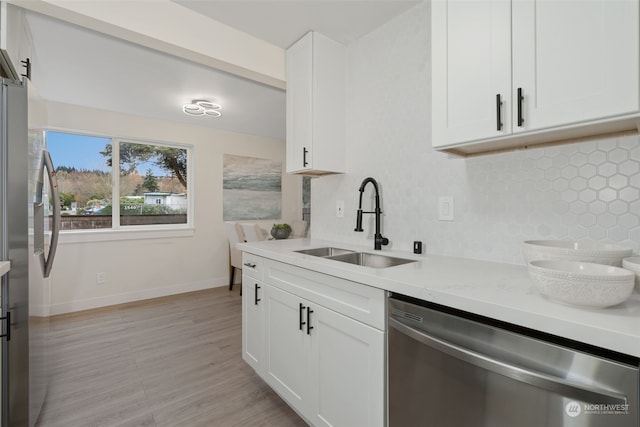 kitchen with sink, light stone counters, backsplash, white cabinets, and appliances with stainless steel finishes