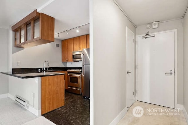 1105 Spring St Unit 701, Seattle, WA 98104 - kitchen with appliances with stainless steel finishes, brown cabinets, a baseboard heating unit, dark countertops, and a peninsula