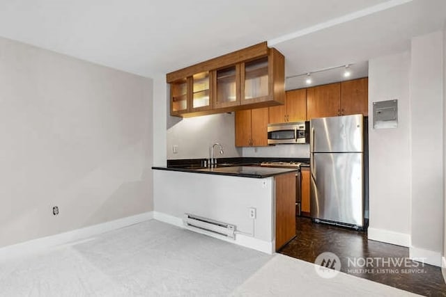 kitchen with rail lighting, sink, appliances with stainless steel finishes, and a baseboard radiator