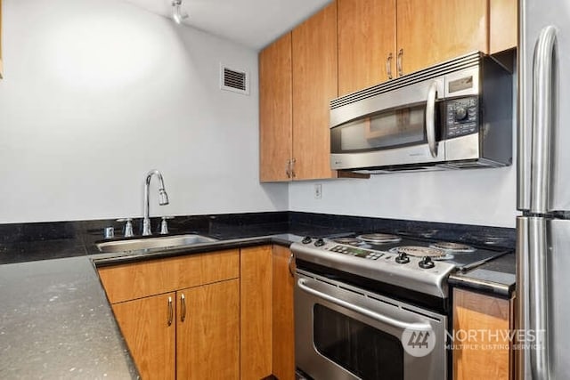 1105 Spring St Unit 701, Seattle, WA 98104 - kitchen featuring stainless steel appliances, a sink, and brown cabinetry