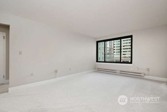 carpeted empty room featuring a baseboard radiator