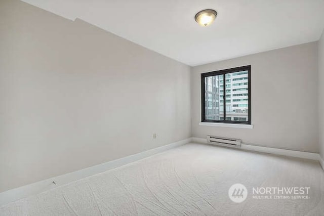 carpeted spare room featuring vaulted ceiling and a baseboard radiator