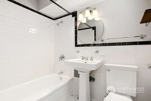 bathroom featuring tile walls, tiled shower / bath combo, and toilet