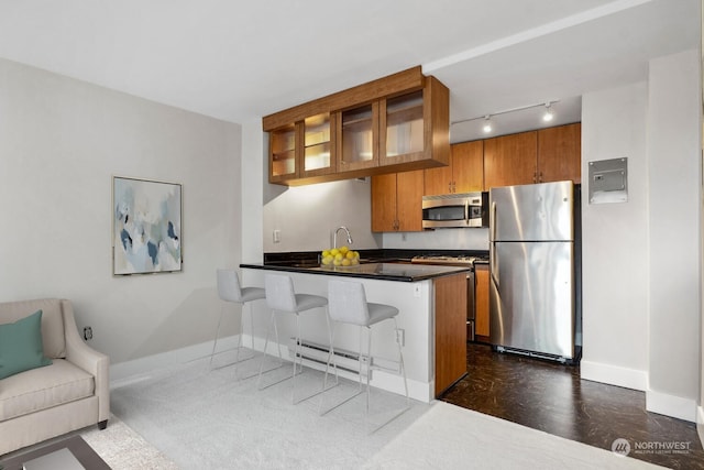 kitchen featuring kitchen peninsula, stainless steel appliances, a baseboard radiator, dark hardwood / wood-style floors, and a breakfast bar area