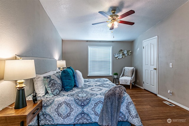 bedroom featuring ceiling fan, dark wood-type flooring, and a textured ceiling