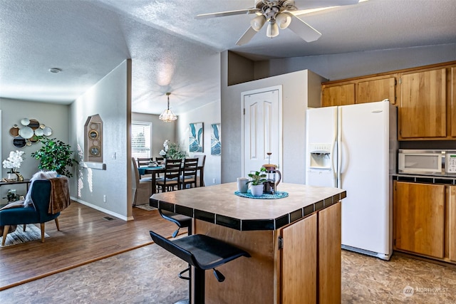 kitchen with ceiling fan, tile countertops, decorative light fixtures, white appliances, and a kitchen island