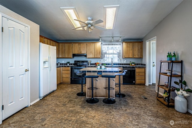 kitchen featuring a kitchen breakfast bar, extractor fan, ceiling fan, black appliances, and a kitchen island