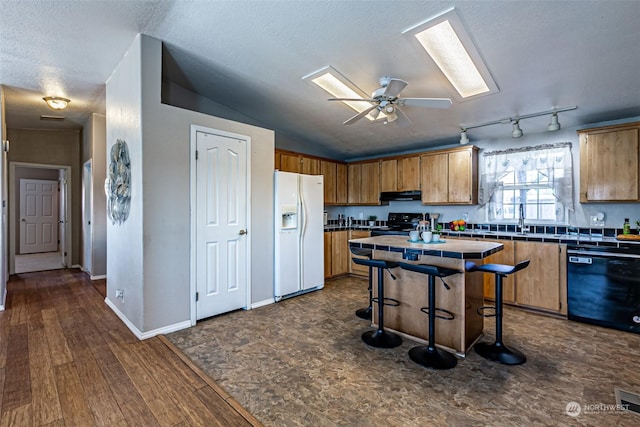 kitchen featuring tile countertops, lofted ceiling, black appliances, ceiling fan, and extractor fan